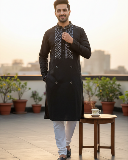 Man wearing a black silk Kurti Connection USA kurta with intricate mirror work and white pajama pants on a rooftop.