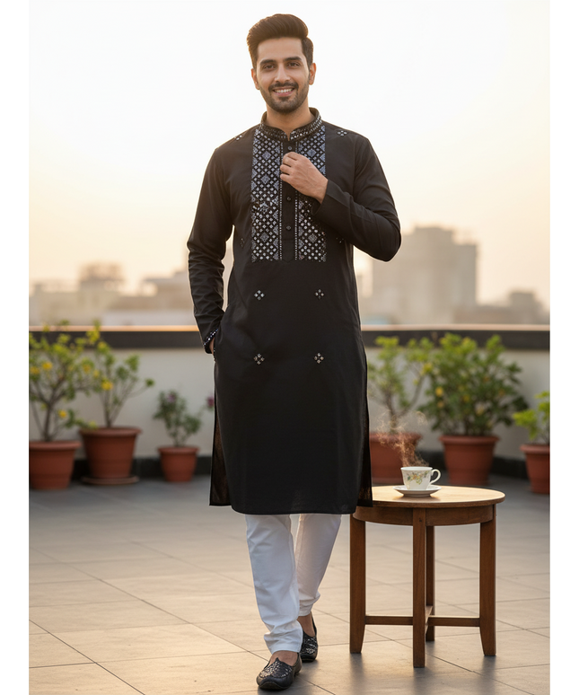 Man wearing a black silk Kurti Connection USA kurta with intricate mirror work and white pajama pants on a rooftop.