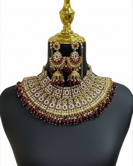 Kurti Connection USA bridal necklace set featuring gold-tone metal, white stones, and deep red beads on a mannequin.