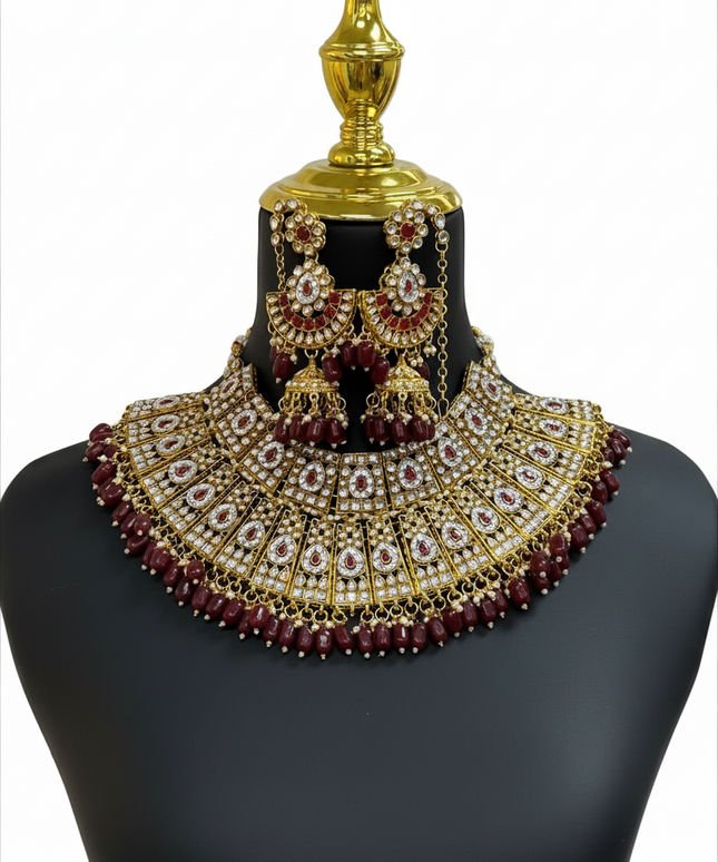 Kurti Connection USA bridal necklace set featuring gold-tone metal, white stones, and deep red beads on a mannequin.