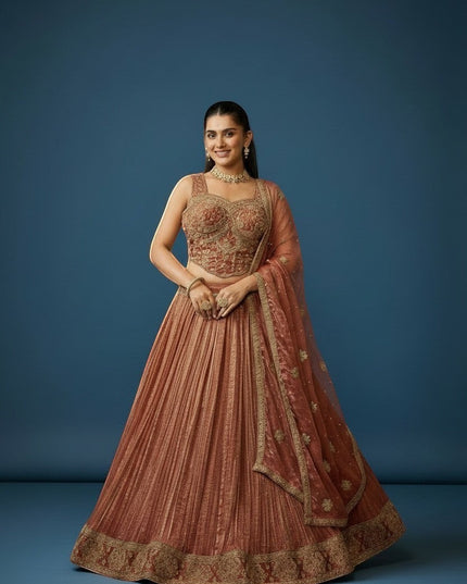 Kurti Connection USA embroidered lehenga set in warm rust with gold detailing. Features a fitted, embellished blouse and pleated skirt with ornate border.