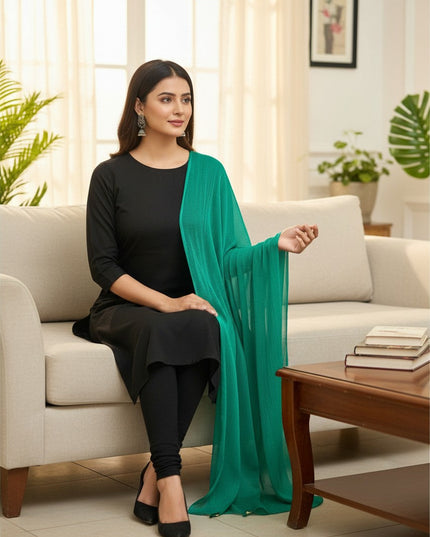 Model wearing a Kurti Connection USA emerald green chiffon dupatta draped over a black ethnic outfit on a sofa
