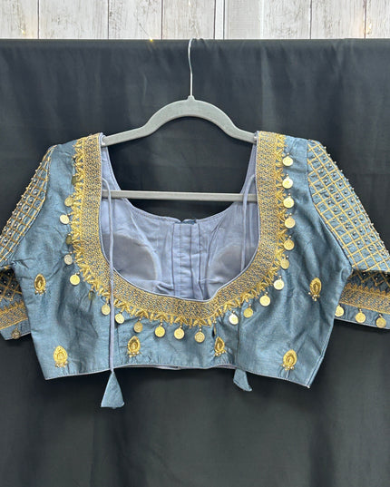 Kurti Connection USA grey silk blouse with intricate gold Maggam embroidery and hanging coin details on a hanger.
