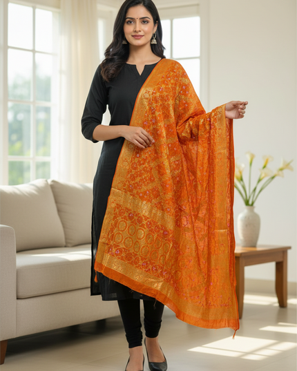 Kurti Connection USA orange Bandhani gharchola dupatta with gold zari border worn by a woman in a black kurta set.