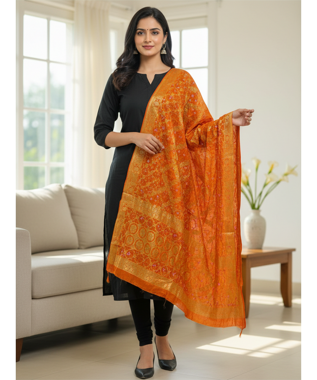 Kurti Connection USA orange Bandhani gharchola dupatta with gold zari border worn by a woman in a black kurta set.