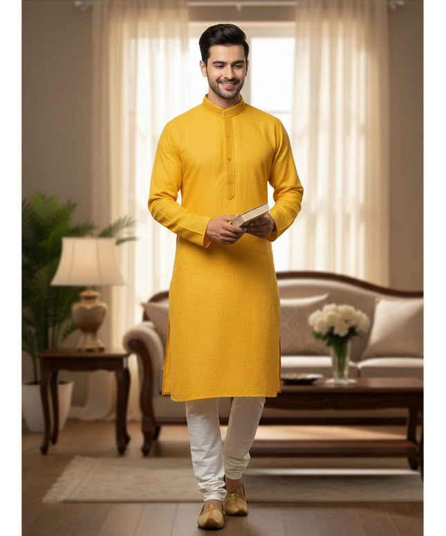 Man wearing a Kurti Connection USA yellow textured kurta with white pajama pants in a bright living room setting.